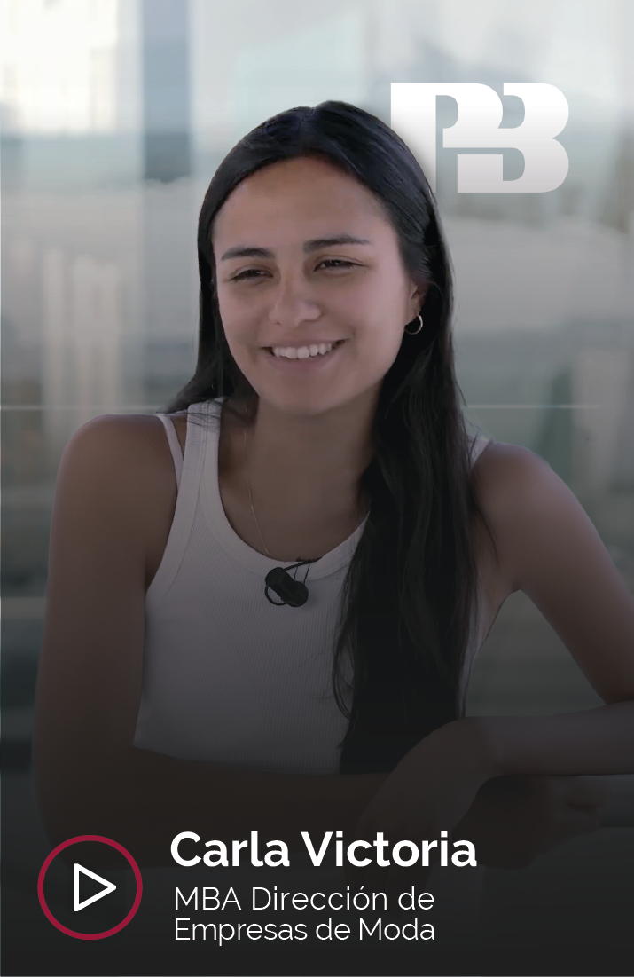 Carla Victoria, estudiante del MBA en Dirección de Empresas de Moda, sonriendo durante una entrevista. Lleva puesto un micrófono de solapa y aparece el logotipo de Pull And Bear en la esquina superior derecha que representa su afiliación.