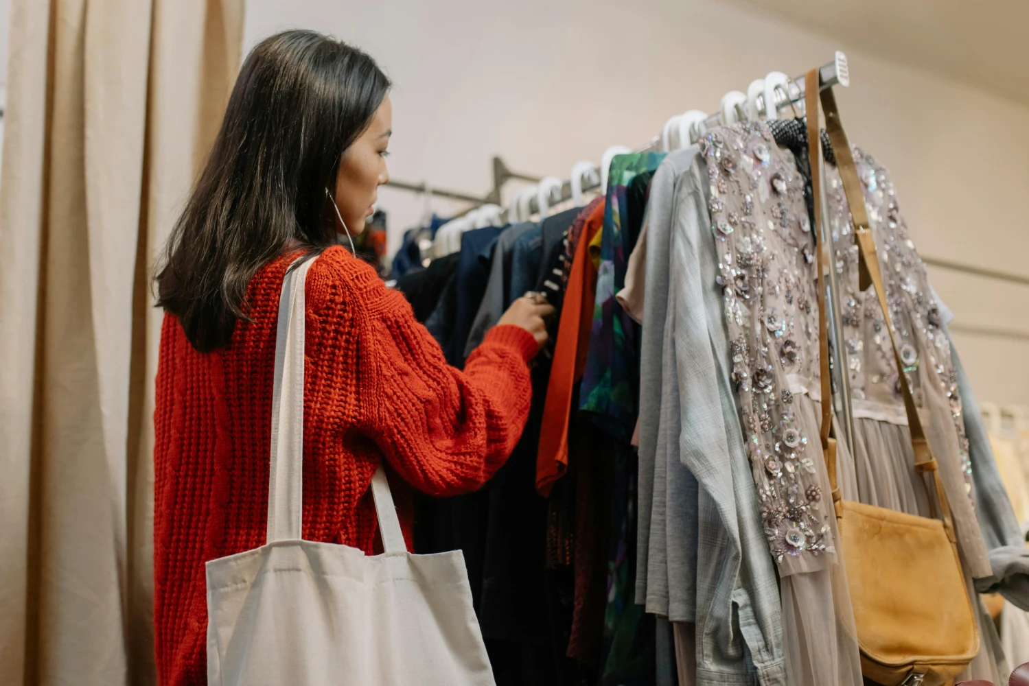 Mujer en una tienda de segunda mano escogiendo ropa. Moda circular, el futuro del negocio está en el reciclaje y la reutilización.